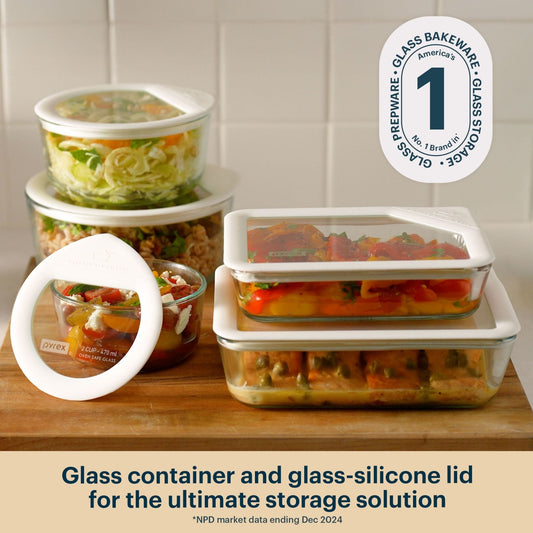 Pyrex glass food storage containers with white silicone clear lids, filled with prepared meals, on a kitchen countertop.