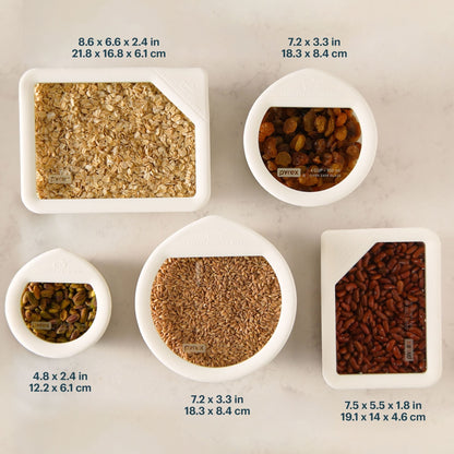 Assorted Pyrex glass food storage containers with clear lids, filled with dry foods and labeled with size dimensions.